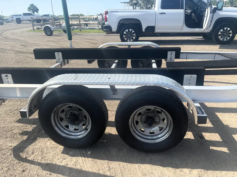 Slide: The Image of Trailer for 2017 Boston Whaler 230 Outrage, parked on sandy ground near a white truck. - 22