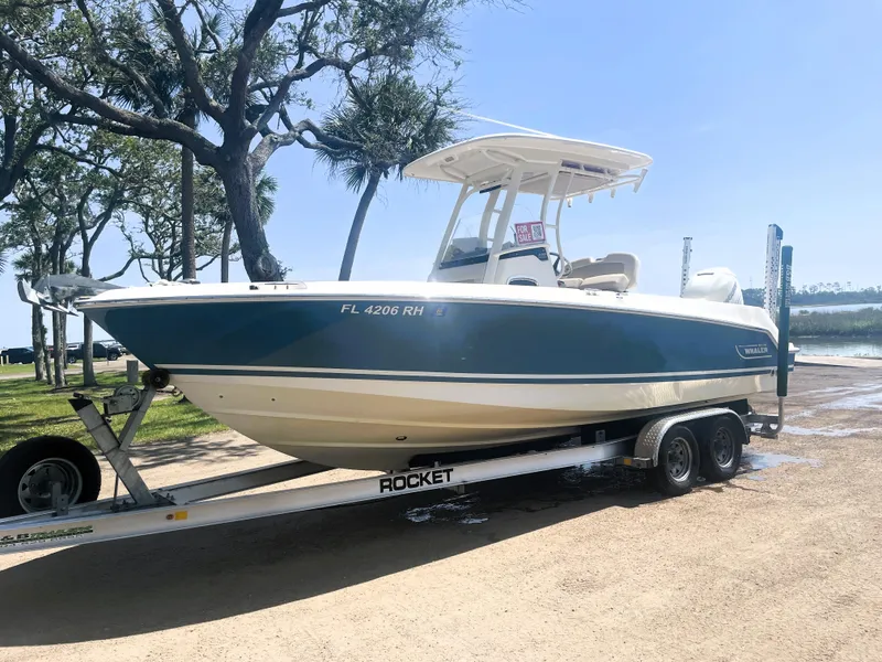 Slide: The Image of 2017 Boston Whaler 230 Outrage boat on trailer, parked near trees. - 3