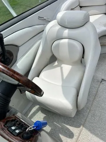 Slide: The Image of 2005 Crownline 216 LS boat interior with white leather seat and wooden steering wheel. - 22