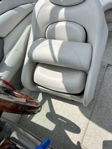 Slide: The Image of 2005 Crownline 216 LS boat interior with plush white seating and wooden steering wheel. - 23