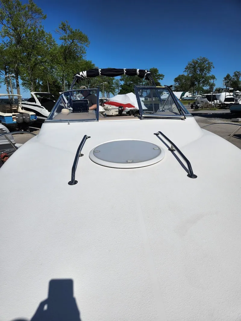 Slide: The Image of 2006 Larson Cabrio 260 boat with sleek design, docked under clear blue sky. - 12