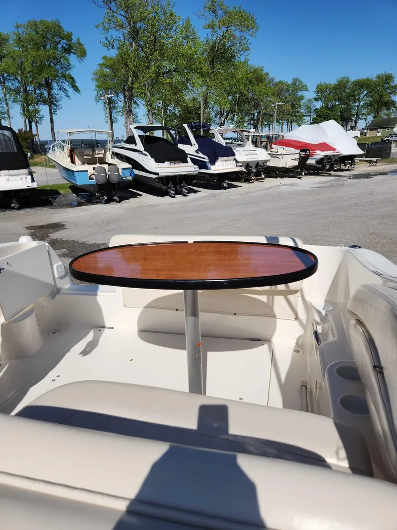 Slide: The Image of 2006 Larson Cabrio 260 boat interior with table, surrounded by other boats in a marina. - 21
