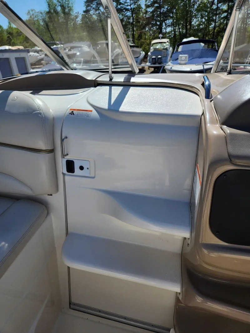 Slide: The Image of 2006 Larson Cabrio 260 boat interior with seating and steps, surrounded by other boats. - 23