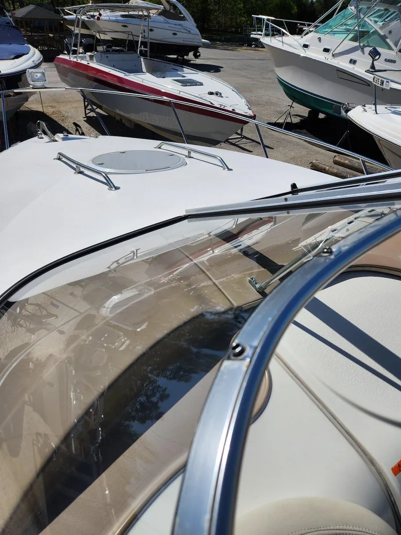 Slide: The Image of 2006 Larson Cabrio 260 boat with windshield, docked among other boats. - 24