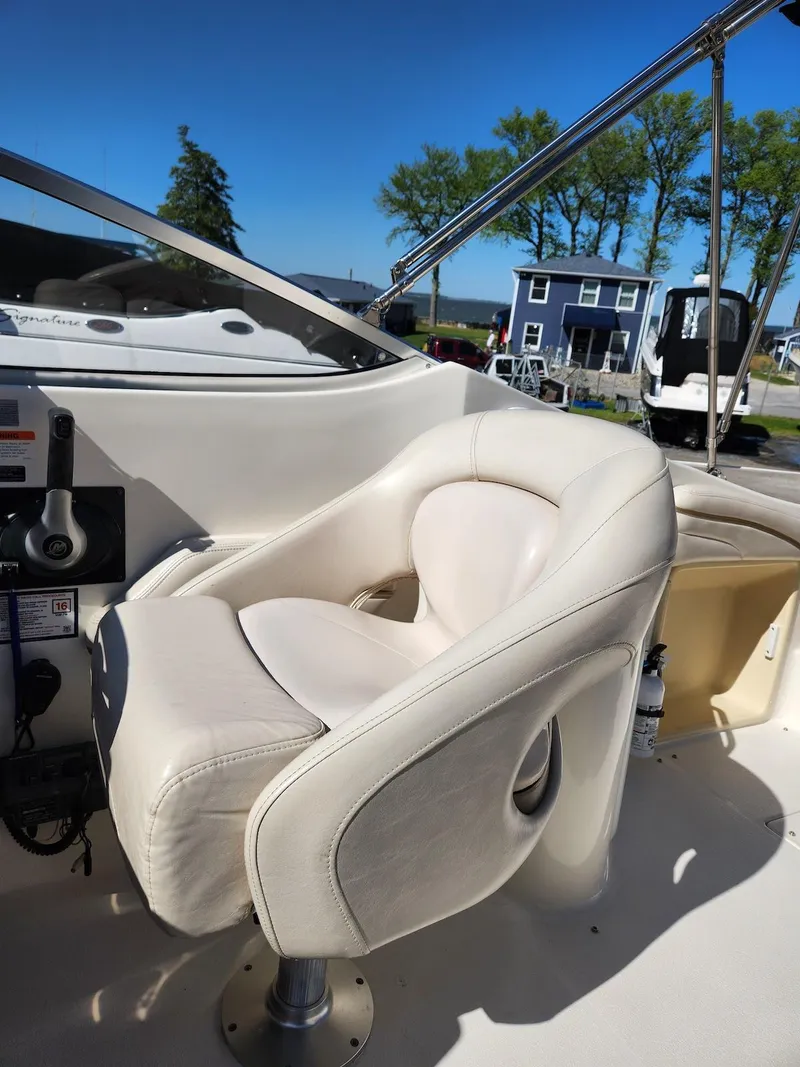 Slide: The Image of 2006 Larson Cabrio 260 boat cockpit with white captain's chair and control panel. - 25