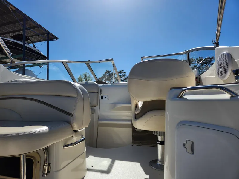 Slide: The Image of 2006 Larson Cabrio 260 boat interior with beige seating under clear blue sky. - 30
