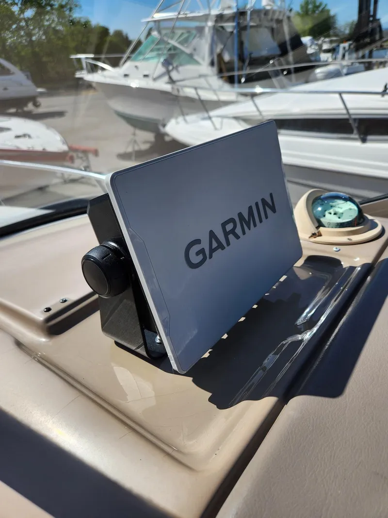 Slide: The Image of Garmin device on 2006 Larson Cabrio 260 boat dashboard with compass, docked boats in background. - 32