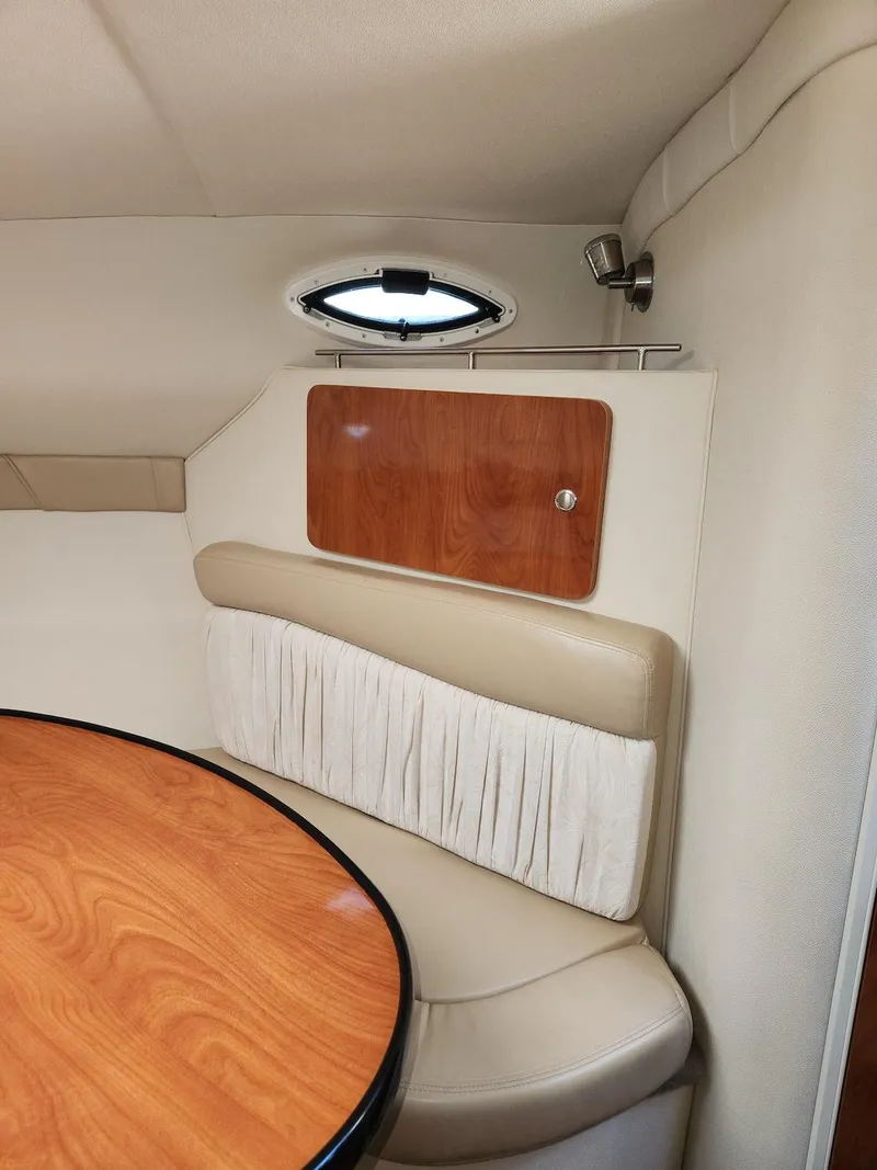 Slide: The Image of 2006 Larson Cabrio 260 cabin interior with wood accents and beige seating. - 34