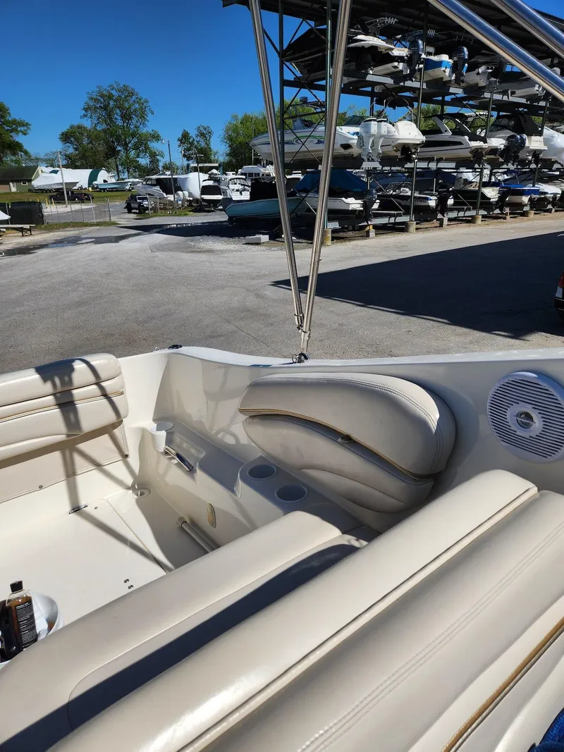 Slide: The Image of 2006 Larson Cabrio 260 boat interior with beige seating, docked at a marina. - 37