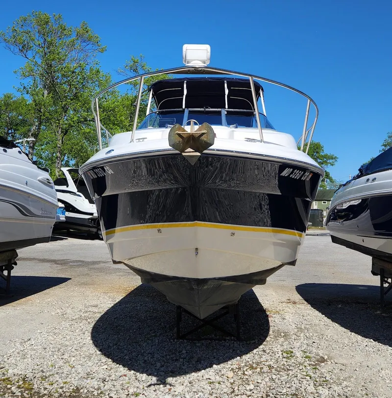 Slide: The Image of 2006 Larson Cabrio 260 boat on display, front view, sunny day, surrounded by trees. - 4