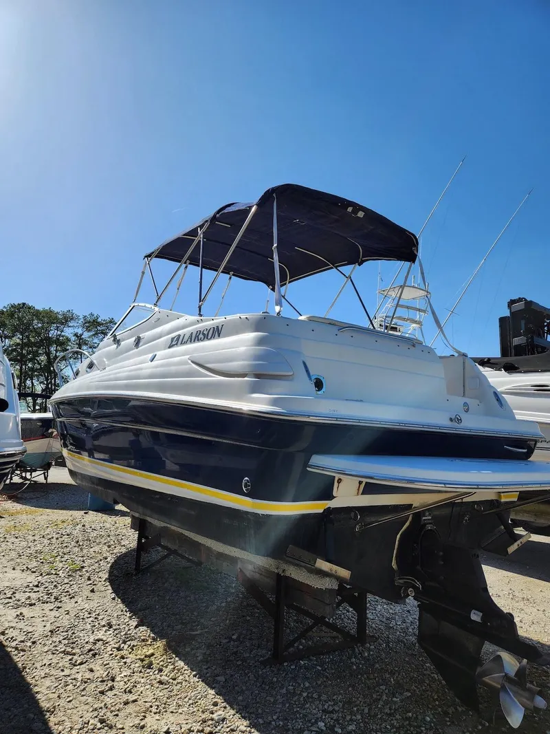 Slide: The Image of 2006 Larson Cabrio 260 boat with canopy, parked on gravel under clear blue sky. - 5