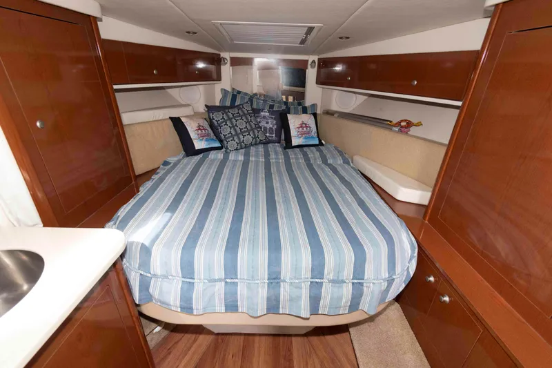 Slide: The Image of 2008 Sea Ray 330 Sundancer cabin with striped bedding and wooden cabinetry. - 17