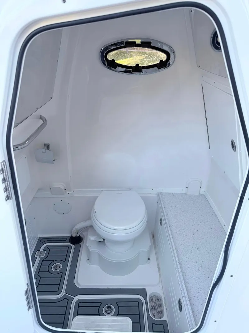 Slide: The Image of 2025 Tidewater 3100 Carolina Bay boat interior with compact marine toilet and porthole. - 18