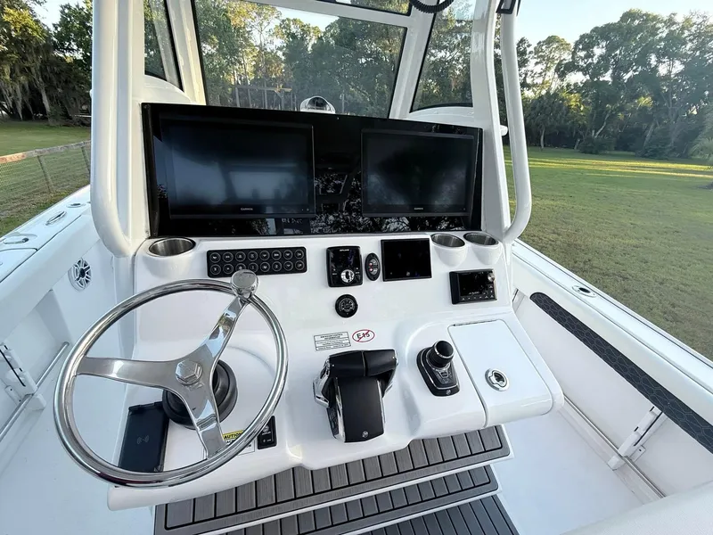 Slide: The Image of 2025 Tidewater 3100 Carolina Bay boat dashboard with dual screens and steering wheel. - 23
