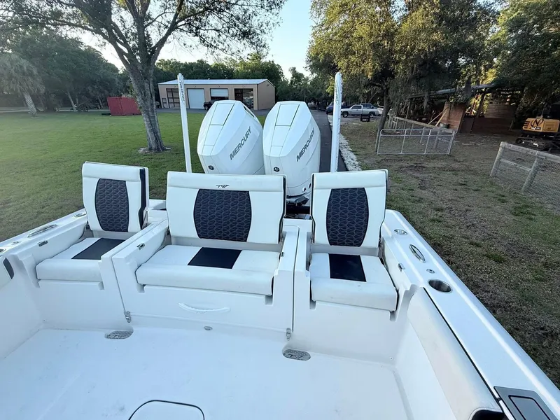 Slide: The Image of 2025 Tidewater 3100 Carolina Bay boat with dual engines and seating, parked on grass. - 28