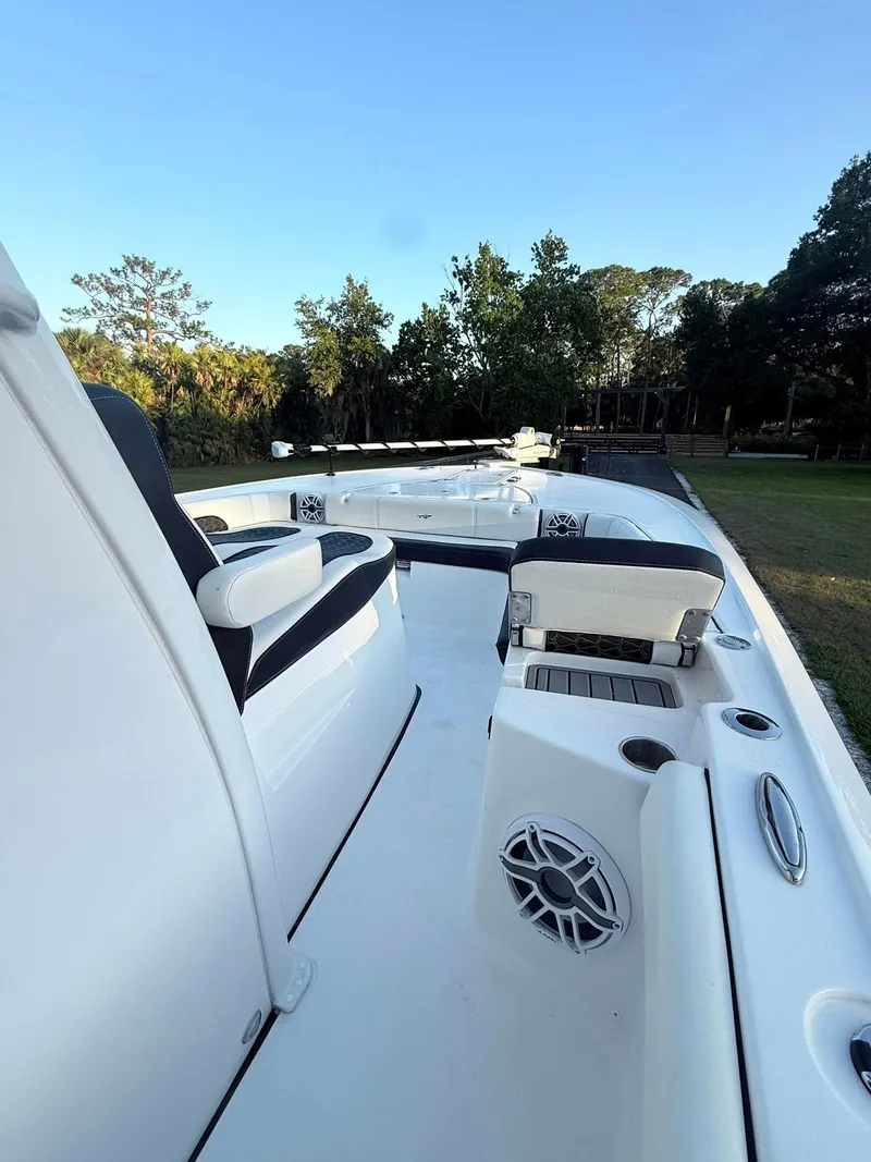 Slide: The Image of 2025 Tidewater 3100 Carolina Bay boat deck with seating and speaker, surrounded by trees. - 30