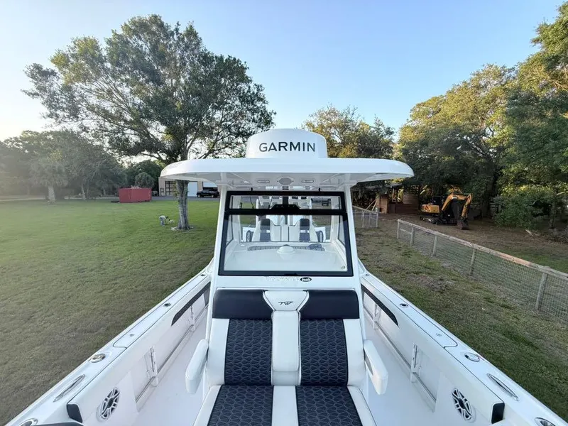 Slide: The Image of 2025 Tidewater 3100 Carolina Bay boat with Garmin equipment, parked on grassy area. - 36