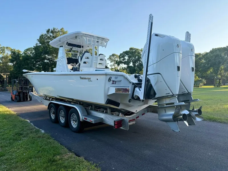 Slide: The Image of 2025 Tidewater 3100 Carolina Bay boat on trailer with dual engines, parked outdoors. - 5