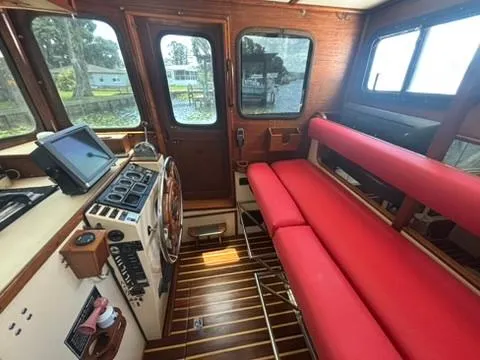 Slide: The Image of 1985 Nordic Tug 32 interior with red seating, wooden accents, and navigation equipment. - 10