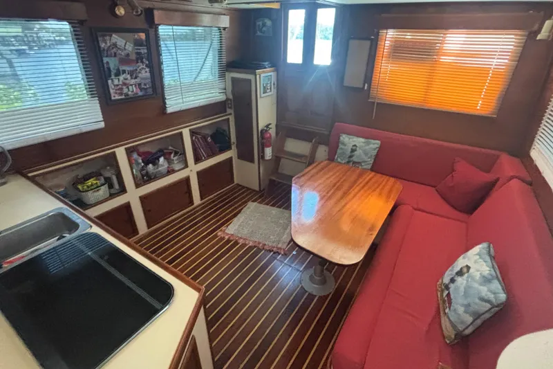 Slide: The Image of 1985 Nordic Tug 32 interior with red seating, wooden table, and striped flooring. - 15