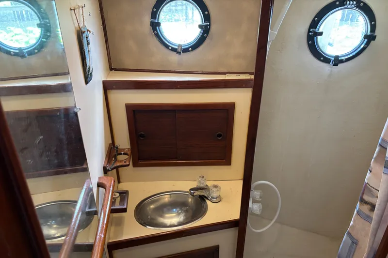 Slide: The Image of 1985 Nordic Tug 32 bathroom with porthole, sink, and wooden cabinetry. - 19