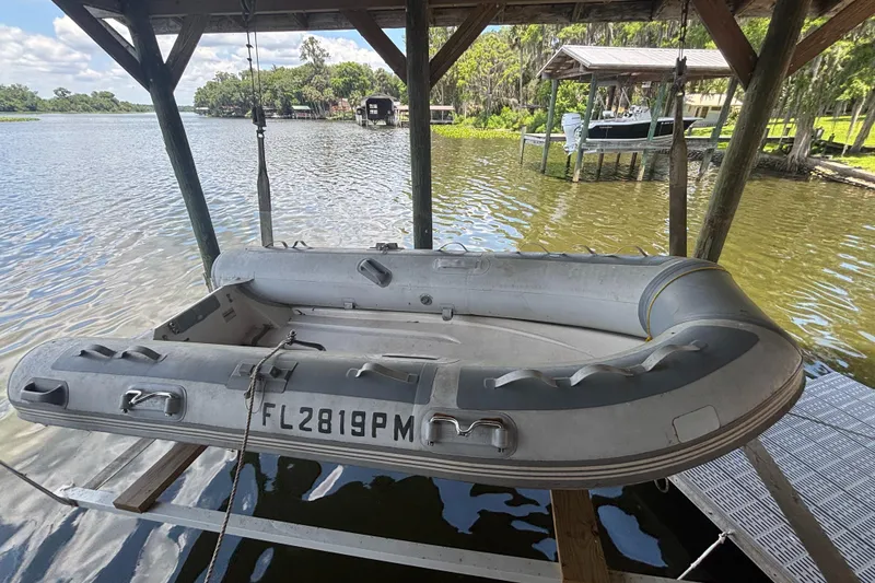 Slide: The Image of Inflatable boat suspended over water, Nordic Tug 32, 1985 model, docked under a wooden shelter. - 22