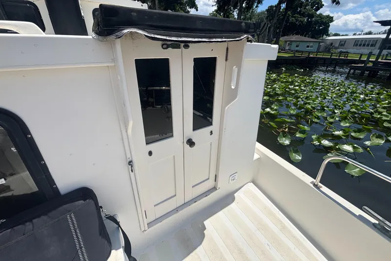Slide: The Image of 1985 Nordic Tug 32 boat deck with white doors and water lilies in the background. - 3