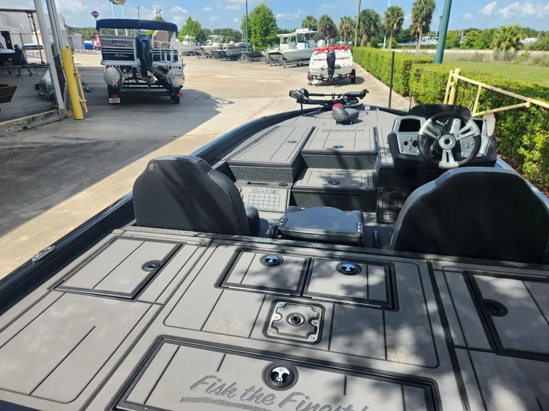 Slide: The Image of 2025 Tracker Savage 215 boat interior with steering wheel and seating, docked under clear skies. - 6