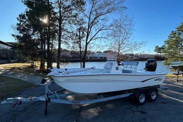 Slide: The Image of 2024 Mako Pro Skiff 19 CC boat on trailer by a scenic lake. - 1