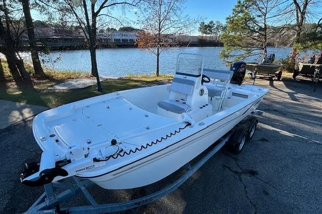 Slide: The Image of 2024 Mako Pro Skiff 19 CC boat on trailer by a scenic lake. - 4