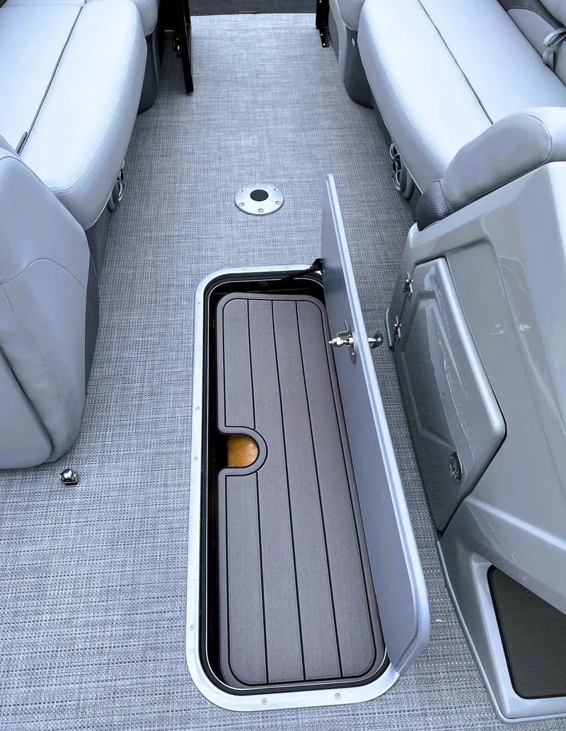 Slide: The Image of 2025 Regency 230 DL3 boat interior with open storage compartment and gray seating. - 4