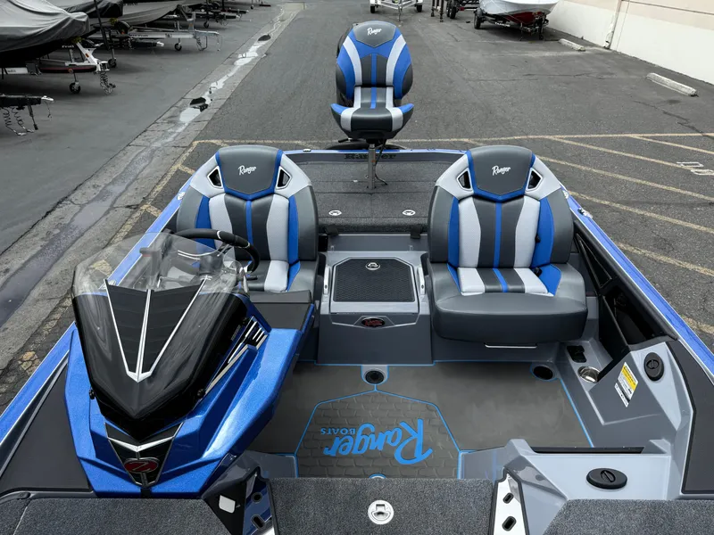 Slide: The Image of 2025 Ranger Z520R Cup-Equipped boat interior with blue and gray seating, parked in a marina. - 12