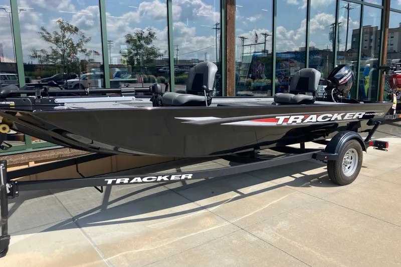 The Image of 2025 Tracker Panfish 17 boat on trailer, displayed outdoors with reflective windows. - 0