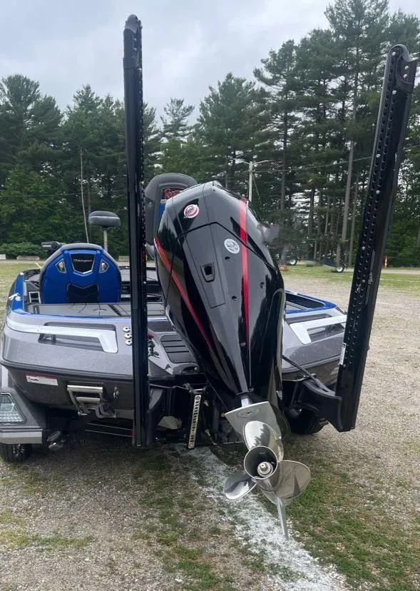 Slide: The Image of 2025 Ranger Z520R boat with powerful outboard motor, parked on gravel, surrounded by trees. - 7