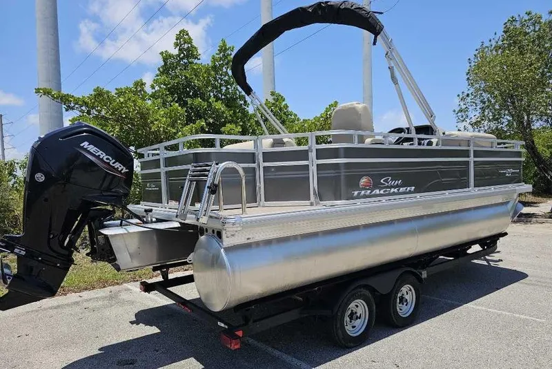 Slide: The Image of 2025 Sun Tracker SportFish 20 DLX pontoon boat on trailer, featuring Mercury outboard motor. - 5