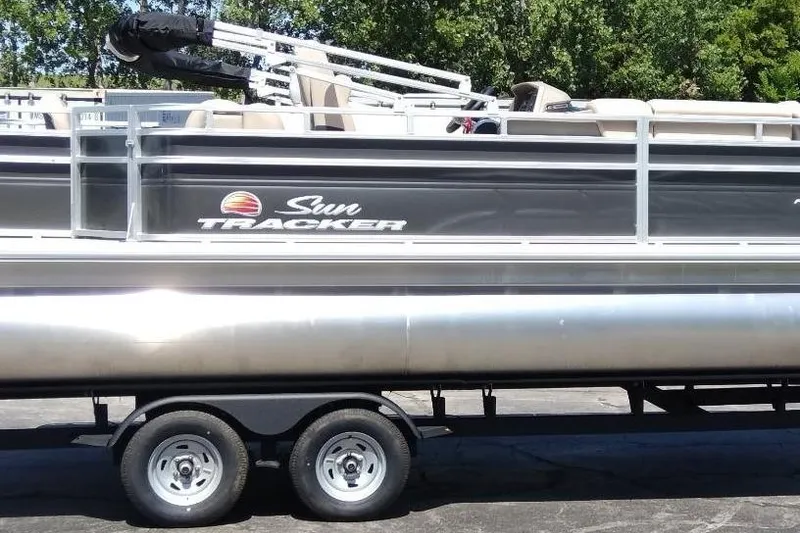 Slide: The Image of 2025 Sun Tracker Fishin' Barge 20 DLX pontoon boat on trailer, side view. - 2