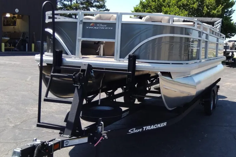 Slide: The Image of 2025 Sun Tracker Fishin' Barge 20 DLX pontoon boat on trailer in parking lot. - 6