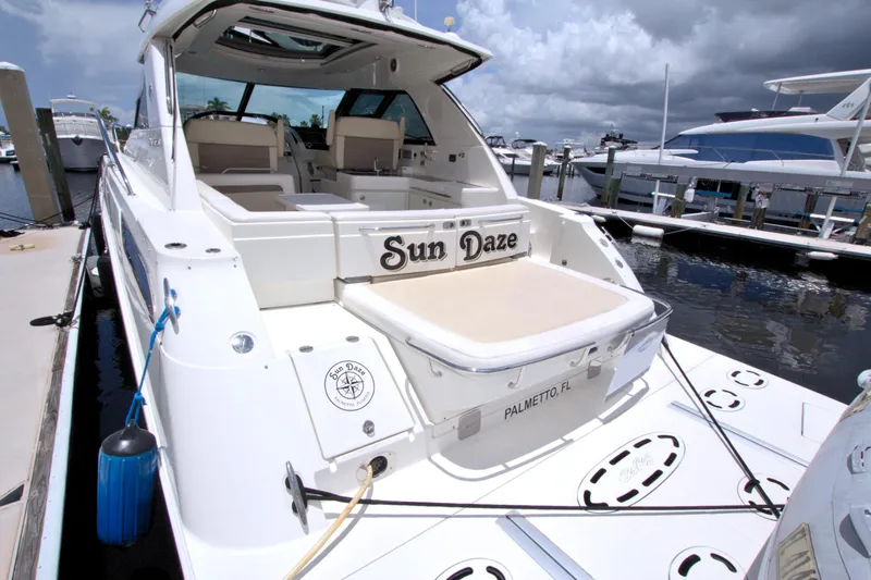 Slide: The Image of 2013 Sea Ray 450 Sundancer yacht docked, featuring spacious deck and seating area. - 11