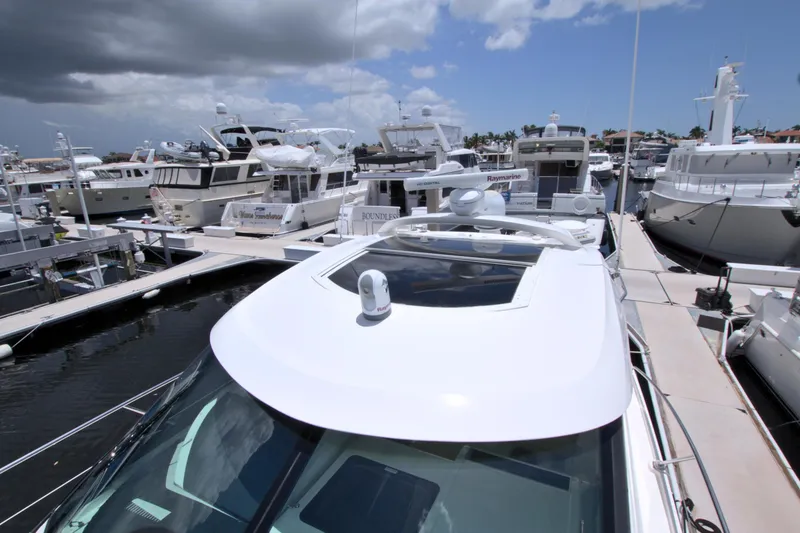 Slide: The Image of 2013 Sea Ray 450 Sundancer docked among luxury yachts under cloudy sky. - 18
