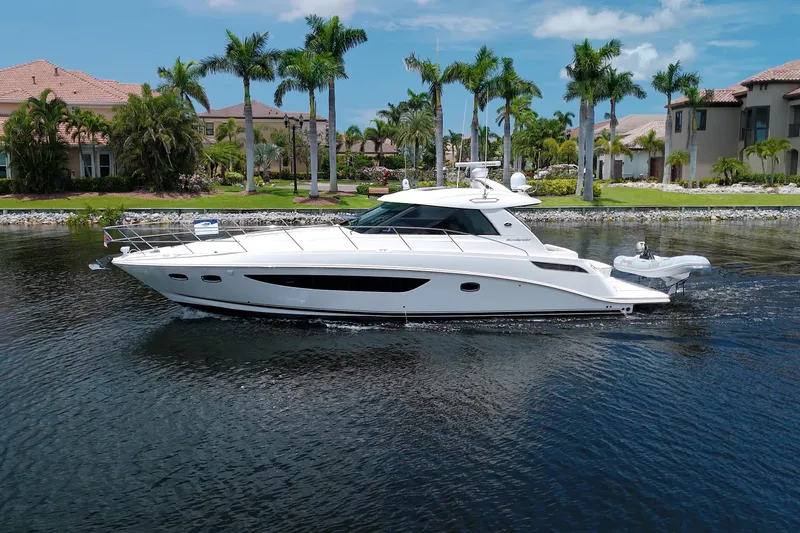 Slide: The Image of 2013 Sea Ray 450 Sundancer yacht cruising on a serene waterway, surrounded by palm trees. - 3