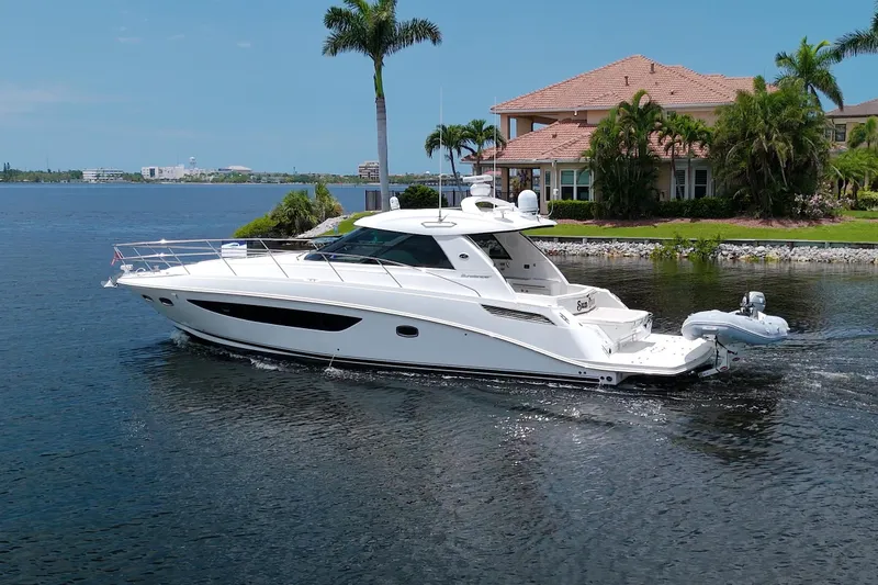 Slide: The Image of 2013 Sea Ray 450 Sundancer yacht cruising near waterfront home. - 4