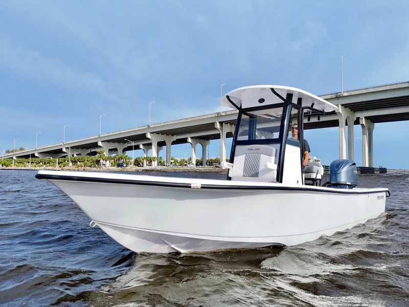 Slide: The Image of 2025 Action Craft 24 Coastal Bay boat cruising under a bridge on a sunny day. - 11