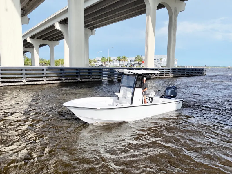 Slide: The Image of 2025 Action Craft 24 Coastal Bay boat cruising under a bridge on a sunny day. - 12