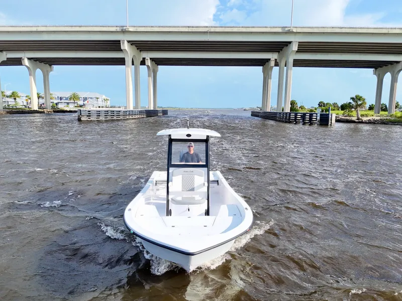 Slide: The Image of 2025 Action Craft 24 Coastal Bay boat cruising under a bridge on a sunny day. - 14