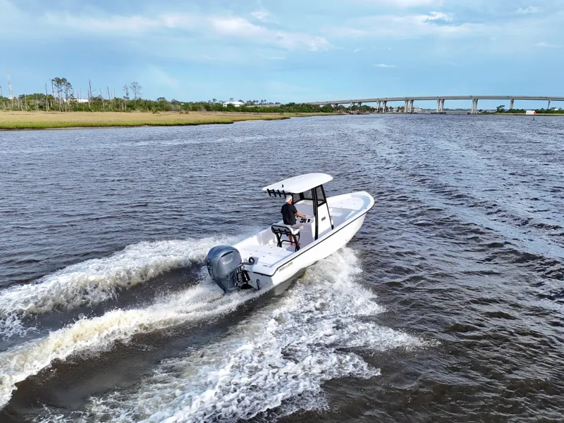 Slide: The Image of 2025 Action Craft 24 Coastal Bay boat cruising on a river near a bridge. - 24