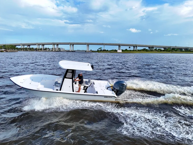 Slide: The Image of 2025 Action Craft 24 Coastal Bay boat cruising on a river with a bridge in the background. - 4