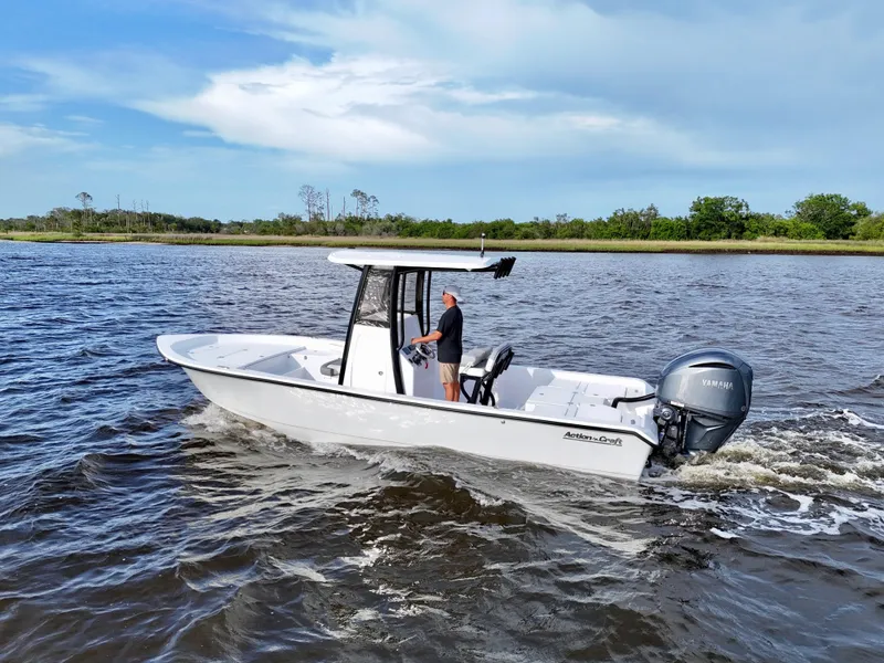 Slide: The Image of 2025 Action Craft 24 Coastal Bay boat cruising on a river with lush greenery. - 6