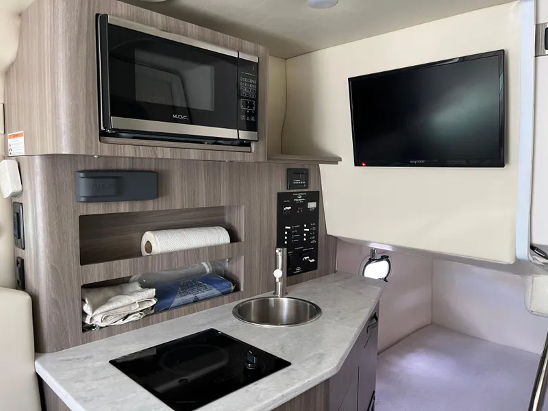 Slide: The Image of 2020 Regal 26 XO boat interior with kitchenette, microwave, sink, and TV. - 35