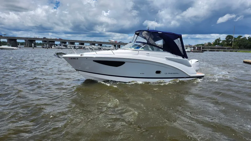 Slide: The Image of 2020 Regal 26 XO boat cruising on a river under a cloudy sky. - 40