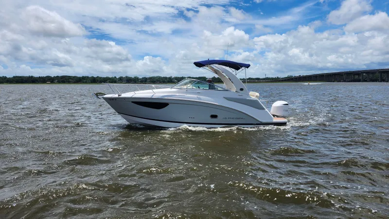 Slide: The Image of 2020 Regal 26 XO boat cruising on a sunny day with a bridge in the background. - 44